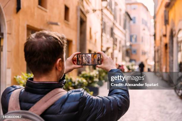 tourist photographing the street in rome historical center using smart phone, italy - trastevere stock-fotos und bilder