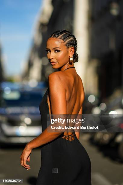 Flora Coquerel wears gold large earrings, a black silk V-neck / halter-neck / black dress long dress, outside Jean-Paul Gaultier, during Paris...