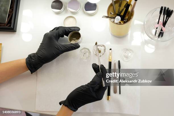 a set of makeup artist brushes for professional makeup in a beauty salon. a woman, a girl, a master in gloves mixes paint before the procedure. the concept of cosmetology, modeling and eyebrow correction. - henné photos et images de collection