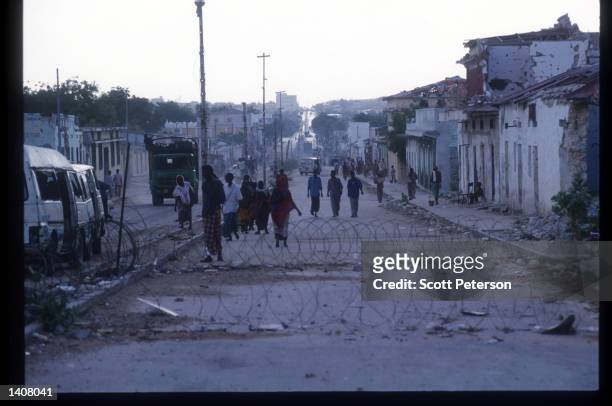 Civilians walk along a destroyed street May 4, 1993 in Mogadishu, Somalia. Following the departure of US forces, UN troops continue the humanitarian...