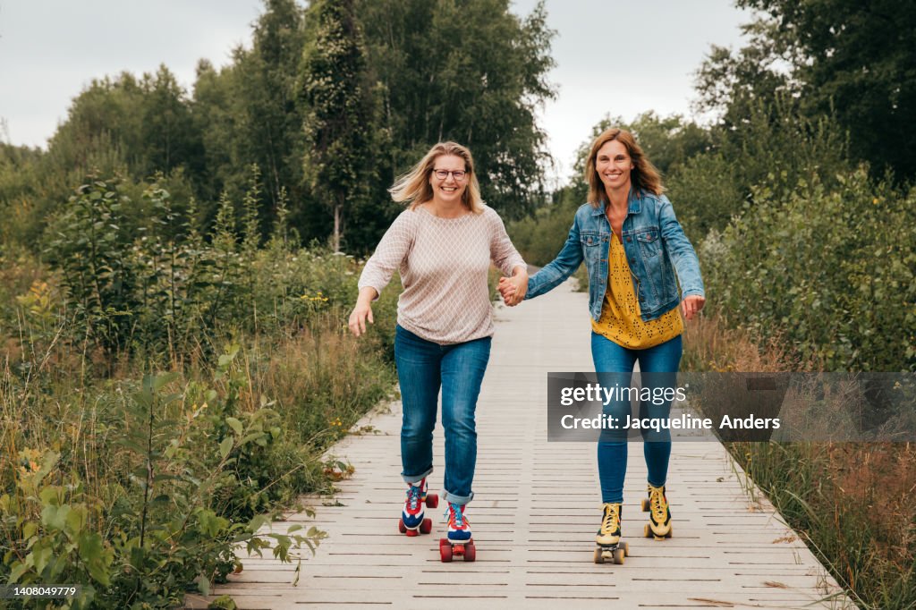 Best ager women having fun outdoors with vintage roller skates and bubbles