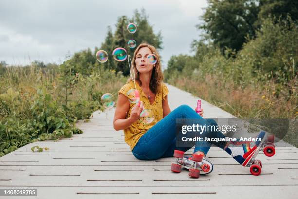 best ager women having fun outdoors with vintage roller skates and bubbles - best ager woman stockfoto's en -beelden