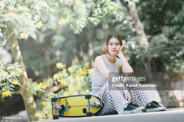 depressed teenage girl with skateboard sitting on ground in the park - skate fail stock-fotos und bilder