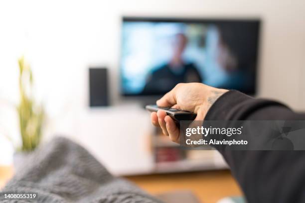 man on sofa changing tv channel - channel ストックフォトと画像