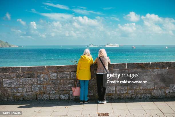 rear view of two senior women looking at sea and harbour - plymouth stockfoto's en -beelden