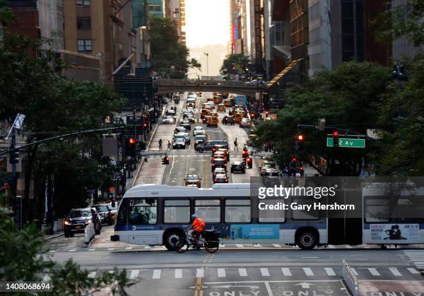 An MTA bus and cyclist cross 42nd Street as the sun sets on July 10 in New York City. The summer Manhattenhenge sunset will take place on July 11 and...