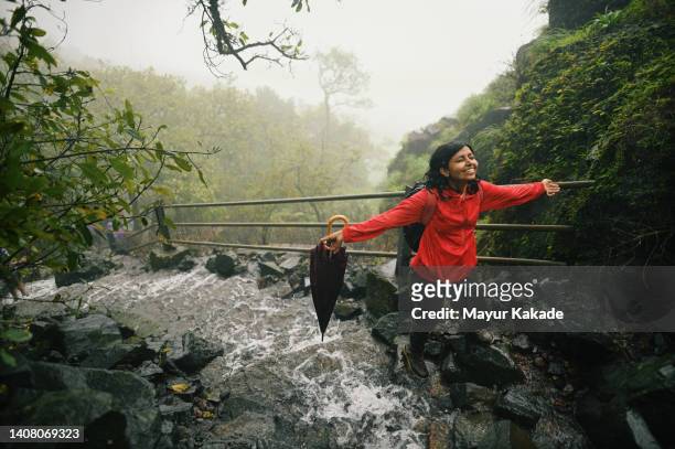 woman enjoying during a trek standing on the steps with flowing water during monsoon - enjoy monsoon photos et images de collection