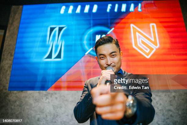 asian chinese emcee esports game show host introducing grand final video game competition on stage with background projector screen - television host stock pictures, royalty-free photos & images