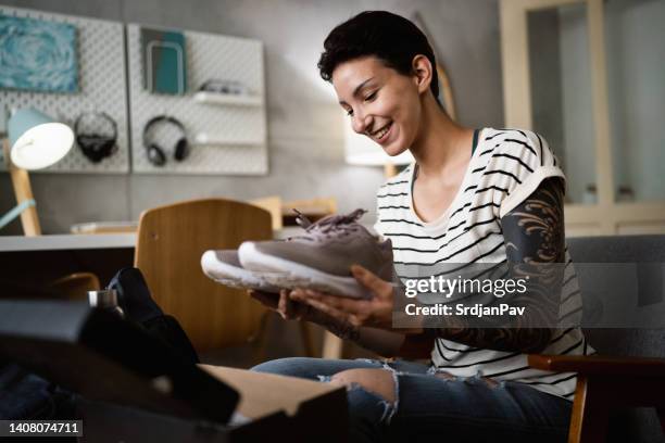 caucasian woman holding and looking at her new sports/workout shoes - new sport content stock pictures, royalty-free photos & images