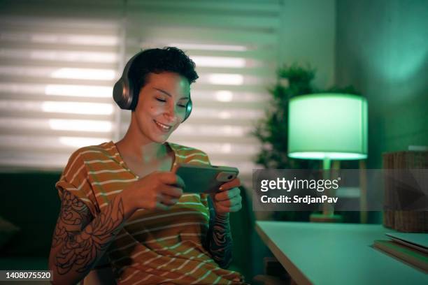 modern caucasian young woman playing video games on mobile phone - gaming mobile stock pictures, royalty-free photos & images