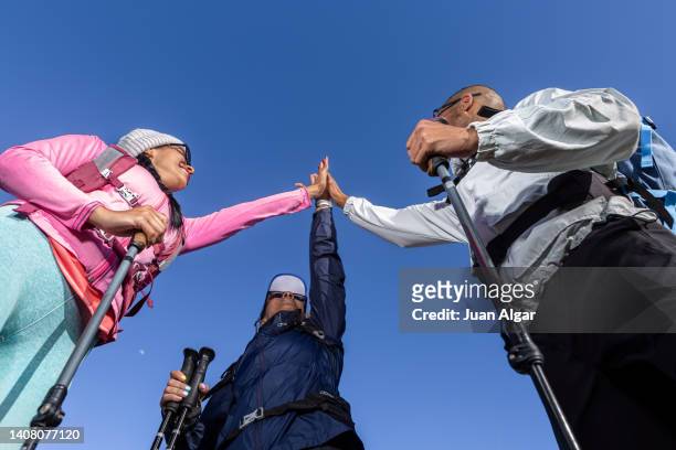 tourists giving high five against blue sky - blue sky friends photos et images de collection