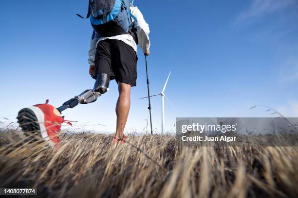 handicapped man walking near wind farm - equipo protésico fotografías e imágenes de stock