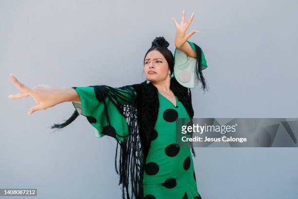 woman, flamenco dancer, dancing in the street, dressed in flamenco costume “traje de flamenca or vestido de gitana”. flamenco, dance, gypsies, tradition, popular, spain, concept. - vestido stock pictures, royalty-free photos & images
