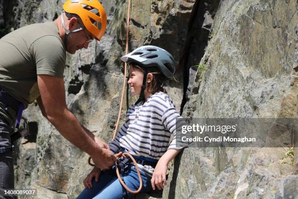 dad tying ropes for his little girl to go rock climbing - love on the rocks stock pictures, royalty-free photos & images