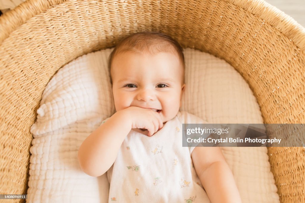 Un bebé de 29 semanas en una acogedora manta de algodón en una canasta de moisés de pastos marinos en una casa moderna neutral