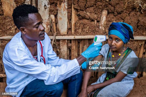 male doctor taking girl temperature in remote village, east africa - doctors without borders 個照片及圖片檔