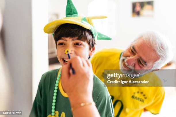 junge, der sein gesicht mit den farben brasiliens malt - face painting kids stock-fotos und bilder