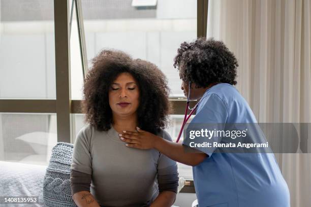 nurse examining transgender woman at home - transgender stockfoto's en -beelden