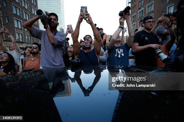 People take photos as the sun sets on 42nd Street in Midtown during Manhattanhenge on July 11, 2022 in New York City.