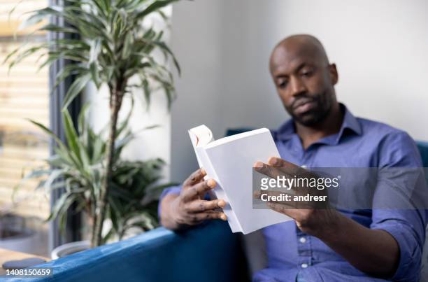 black man reading a book at home - entertainment book edit stock pictures, royalty-free photos & images
