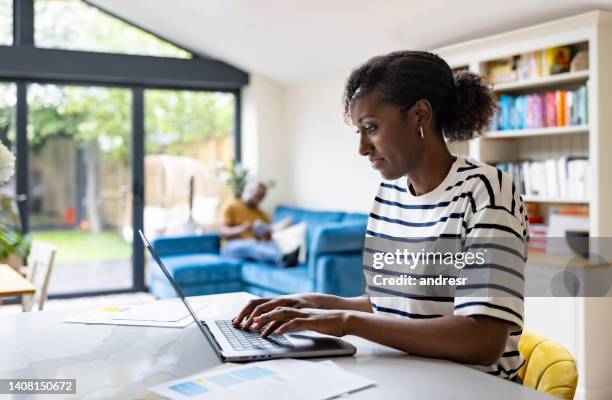 happy black woman working at home on her laptop - blogger woman stock pictures, royalty-free photos & images