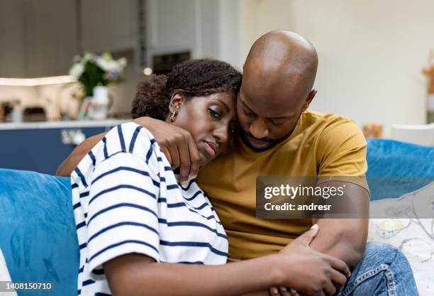 man comforting his wife at home - sad husband stock pictures, royalty-free photos & images