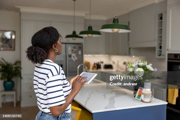 frau, die die lichter in ihrem haus mit einem automatisierten system steuert - dimmer stock-fotos und bilder