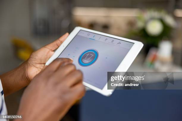 close-up on a woman adjusting the temperature of her house using a mobile app - air conditioner interior wall stock pictures, royalty-free photos & images