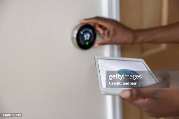 woman adjusting the temperature of her house using a mobile app - air conditioner interior wall stock pictures, royalty-free photos & images