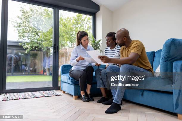 couple buying a house and reviewing the contract with their real estate agent - landlord stock pictures, royalty-free photos & images