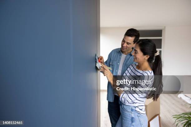 couple choosing a color to paint the walls of their house - couple painting stock pictures, royalty-free photos & images