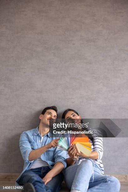couple at home decorating their new house and holding a color swatch - mid adult men stock pictures, royalty-free photos & images