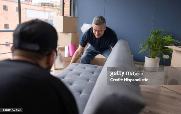 professionelle umzugsunternehmen, die ein sofa aus einer wohnung tragen - möbelpacker stock-fotos und bilder