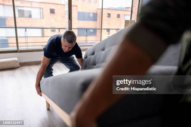 professional movers carrying a sofa out of an apartment - moving service imagens e fotografias de stock