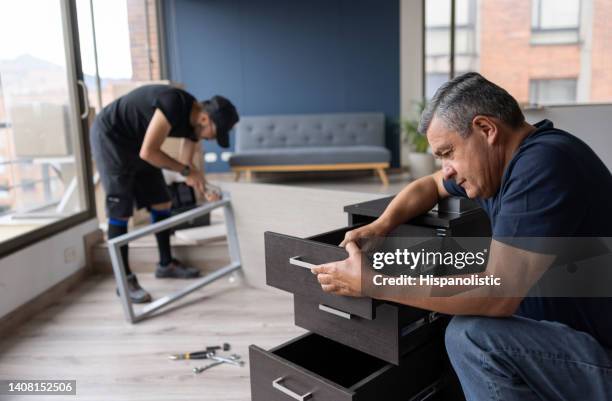 professional movers disassembling pieces of furniture at an apartment - disassembled stock pictures, royalty-free photos & images