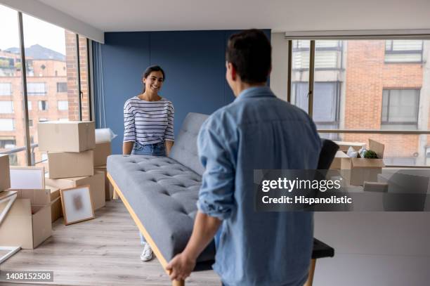 happy couple moving house and carrying a couch together - carrying sofa stock pictures, royalty-free photos & images