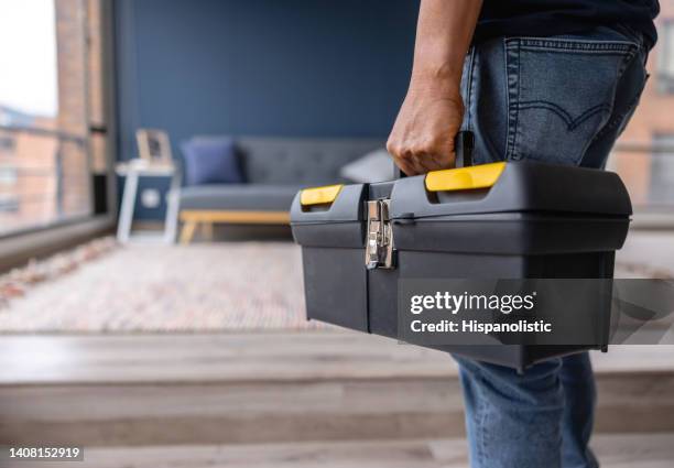 nahaufnahme eines elektrikers, der einen werkzeugkasten trägt, während er in einem haus arbeitet - werkzeugkasten stock-fotos und bilder