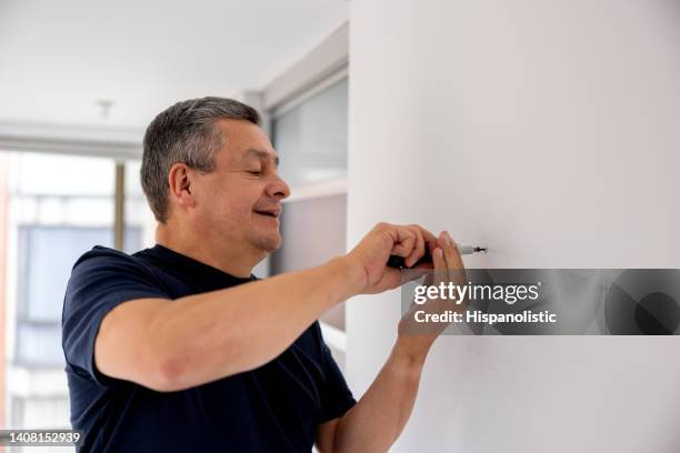 man using a screwdriver to put a screw in the wall - screwdriver stock pictures, royalty-free photos & images