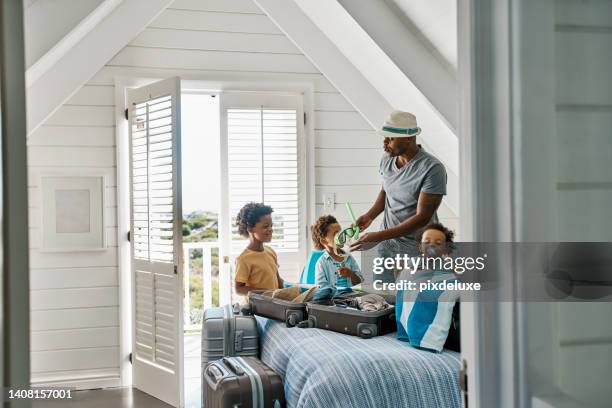 famille noire en vacances d’été avec ses enfants à l’intérieur d’une maison de plage de vacances. papa africain faisant ses valises pour ses enfants pour une journée à la piscine. un homme célibataire voyage avec ses fils et prend soin d’eux - cabine de plage photos et images de collection