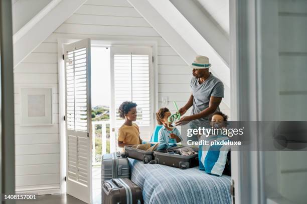 black family on a summer vacation with his kids inside a holiday beach house. african dad packing for his children for a day at the pool. a single man travel with his sons and taking care of them - beach hut stock pictures, royalty-free photos & images
