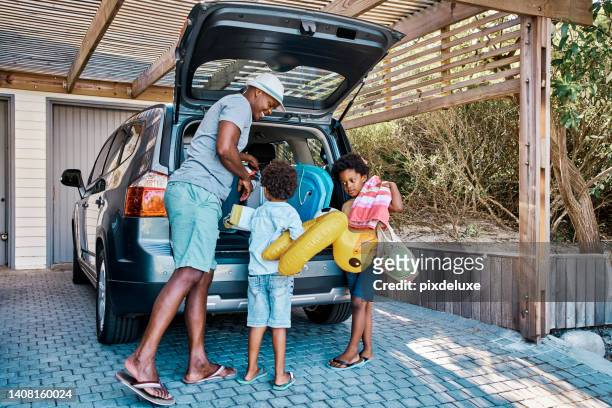 una famiglia che prepara l'auto per partire per le vacanze estive. un felice padre afroamericano e i suoi due graziosi figlicini preparano i bagagli nel suo veicolo per partire per un viaggio, pronti per il tempo di viaggio - trip foto e immagini stock