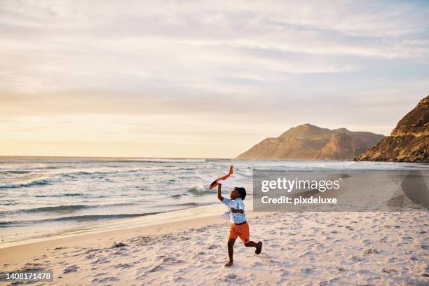 little boy running with a toy on the beach with copy space. child playing with an airplane plaything by the ocean on his holiday vacation. playful, energized kid having fun with an outdoor activity - one boy only stock pictures, royalty-free photos & images