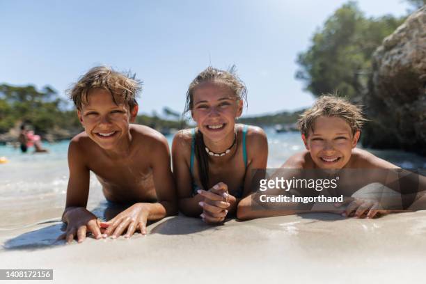 bambini che si divertono nella bellissima baia sulle rive di maiorca, spagna - young teen girl beach foto e immagini stock