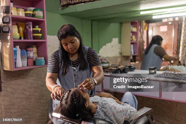 mid adult woman threading eyebrows her customer - eyebrow threading stock-fotos und bilder