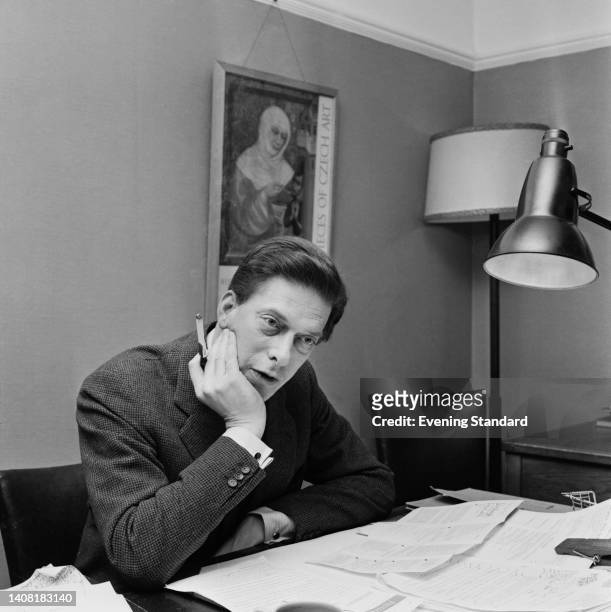 British author and arts administrator George Lascelles, 7th Earl of Harewood , sitting behind a desk, his chin resting in his right hand, in an...