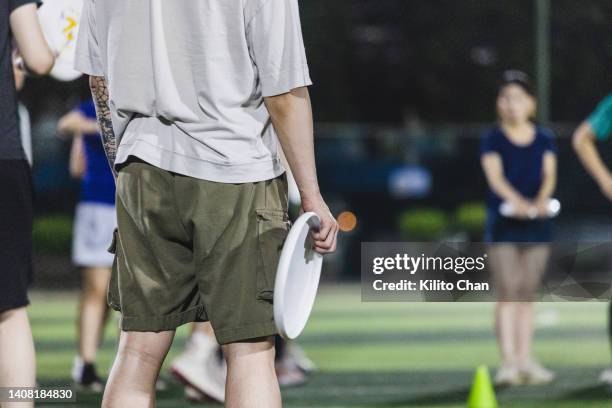 asian friends playing frisbee in a soccer field - frisbee golf stock pictures, royalty-free photos & images