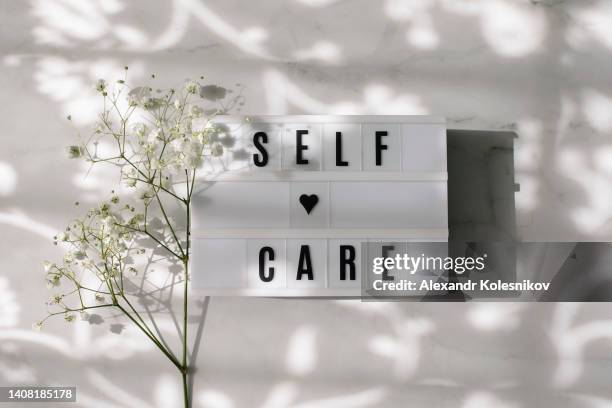 self care words texting on lightbox and flower gypsophila on marble background. - selfishness stock pictures, royalty-free photos & images