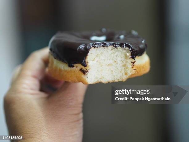 hand holding eating donut topping chocolate - food design stock pictures, royalty-free photos & images