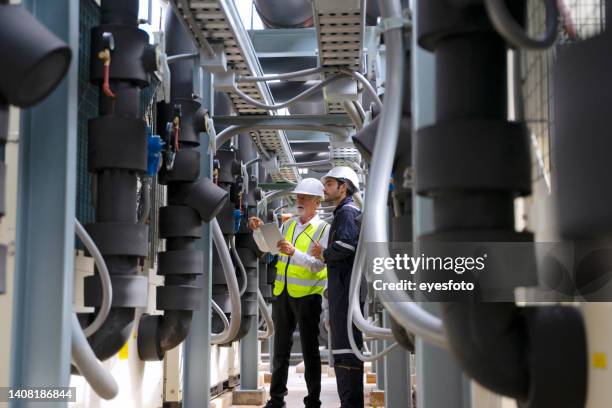 engineer is working on the roof of building. surrounding with high building. - air conditioning cooling tower stock pictures, royalty-free photos & images