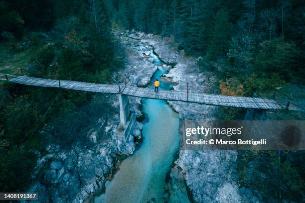 man standing on a suspension bridge above a mountain river - julianische alpen stock-fotos und bilder